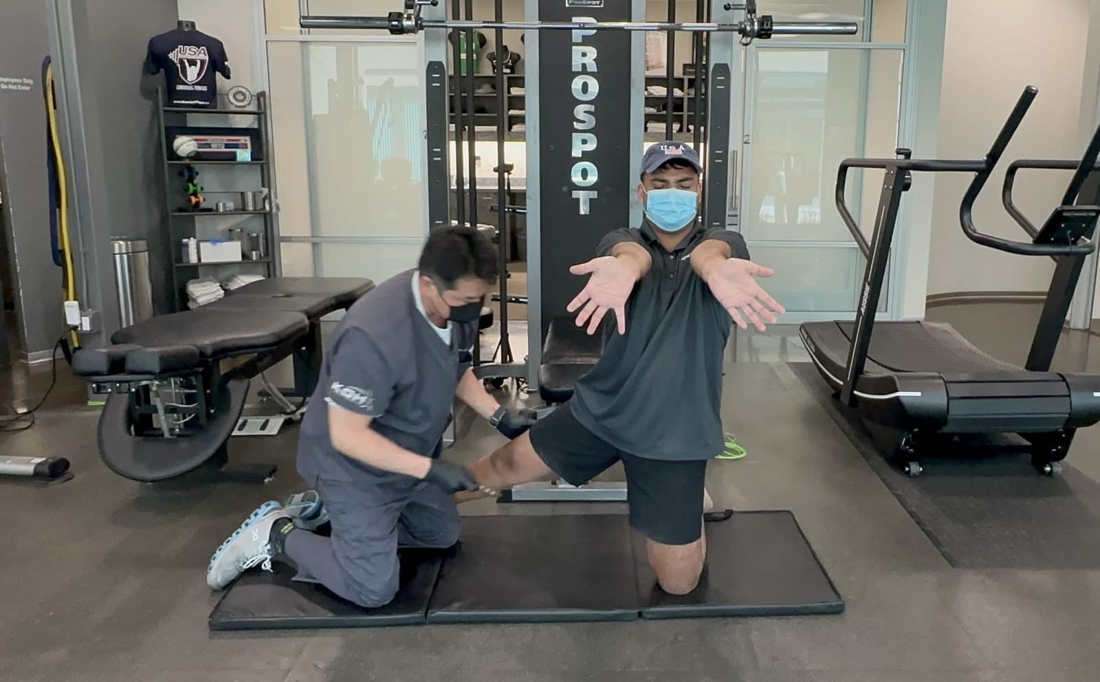 A KOH Physical Therapy Lab therapist assisting a kneeling client with an arm and trunk fascia stretch