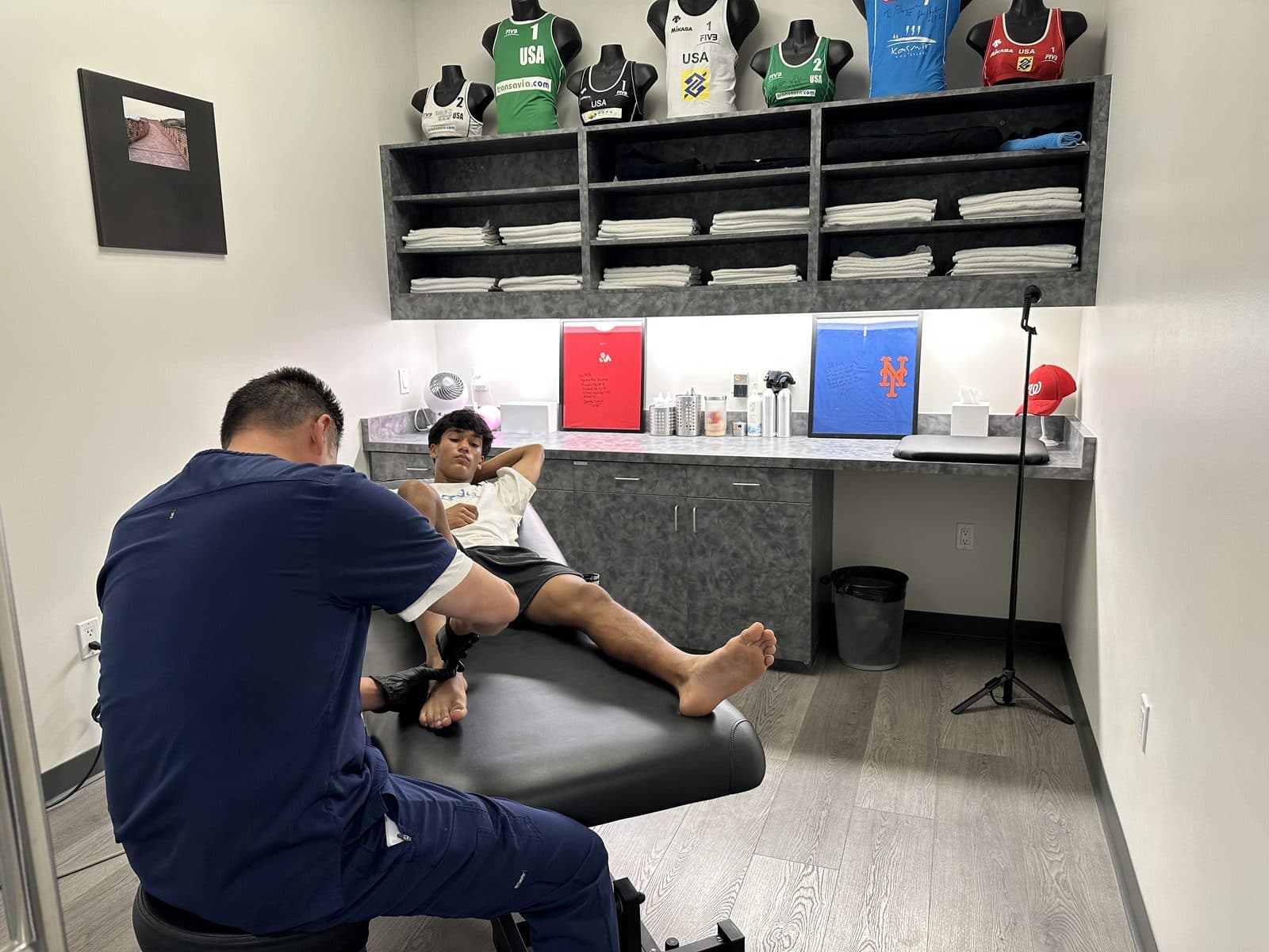 A physical therapist treating a patient's ankle on a treatment table in a KOH Physical Therapy Lab treatment room