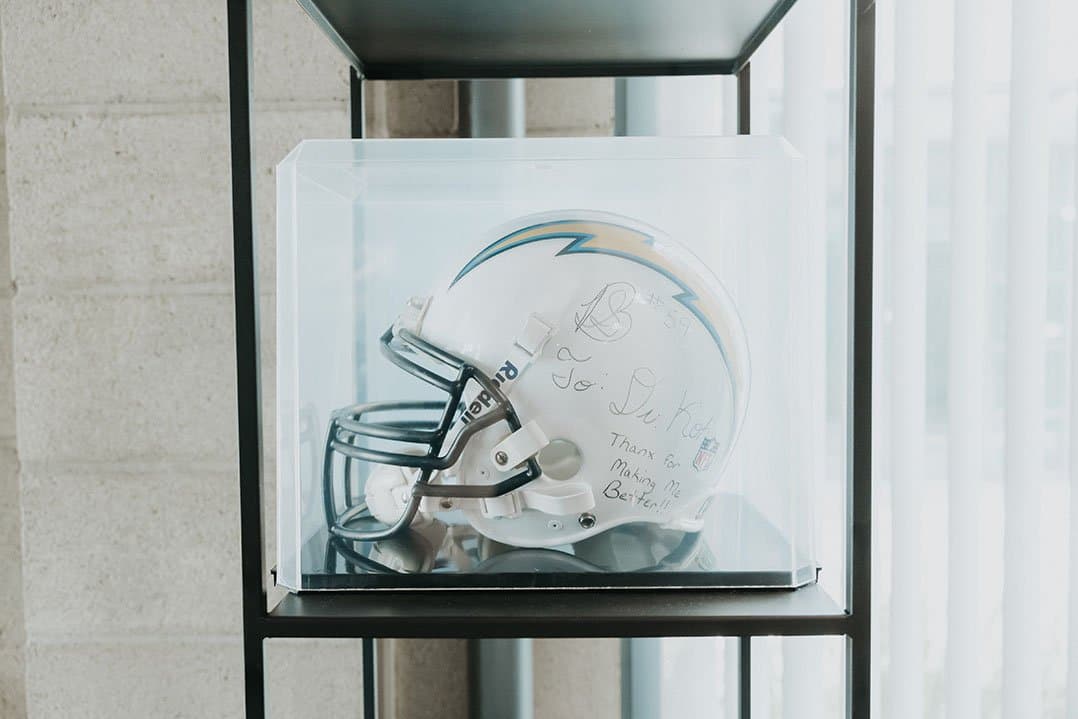 A signed football helmet in a display case, inscribed to Dr. Koh: Thanx for making me better