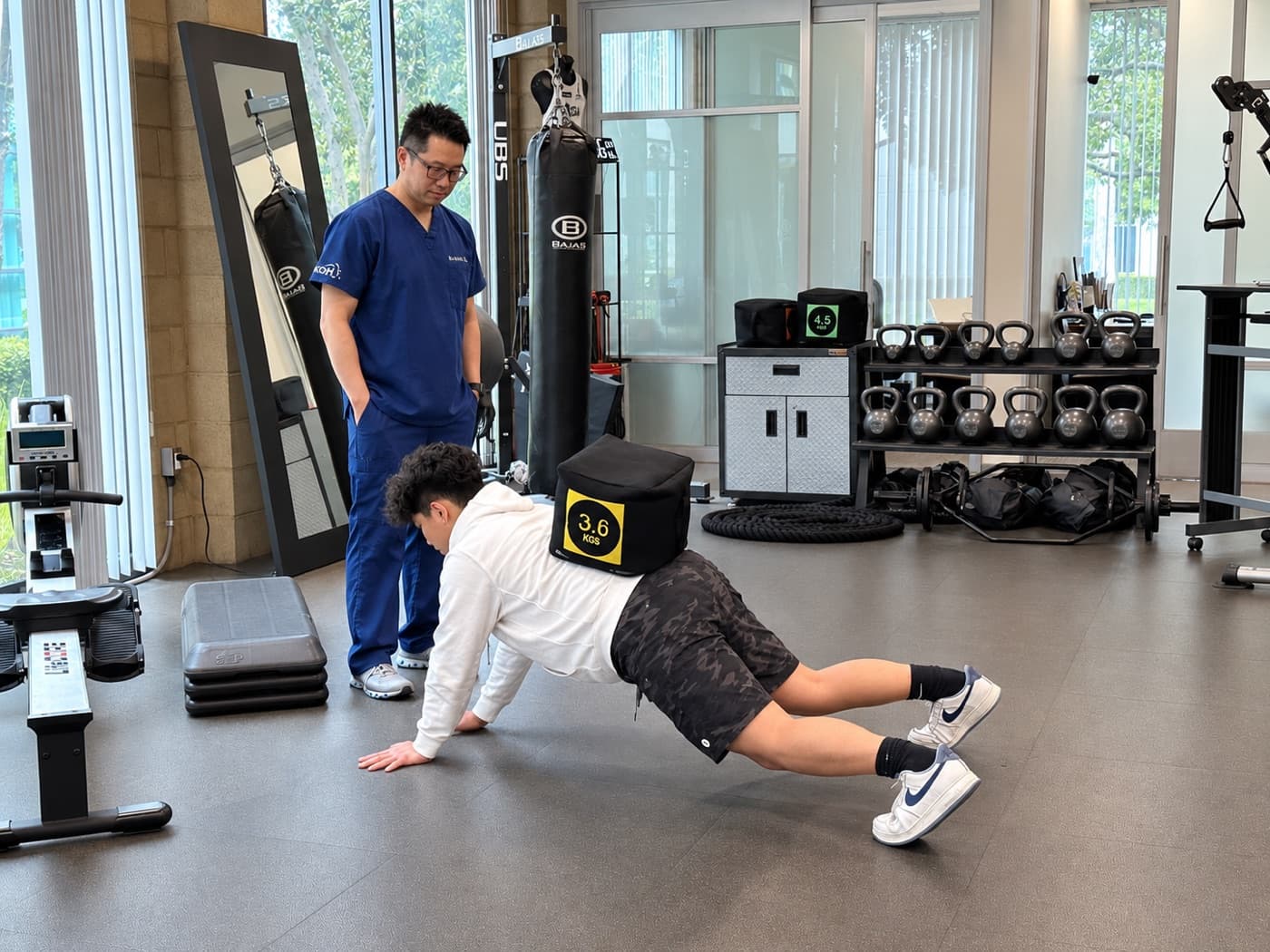 A KOH Physical Therapy Lab physical therapist supervising a client's plank exercise on the clinic training floor