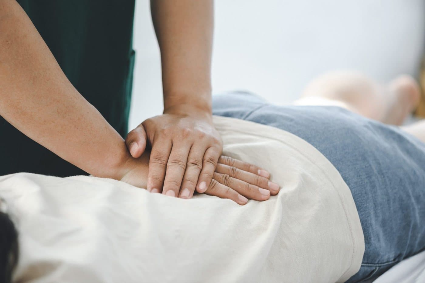 A physical therapist's hands applying manual therapy to a client's lower back