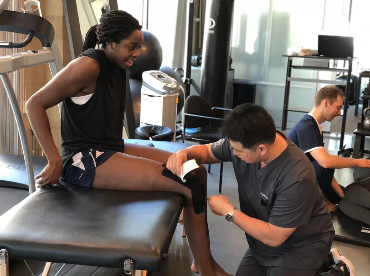 Davis Koh, DPT, applying kinesiology tape to a client's knee in the KOH Physical Therapy Lab clinic
