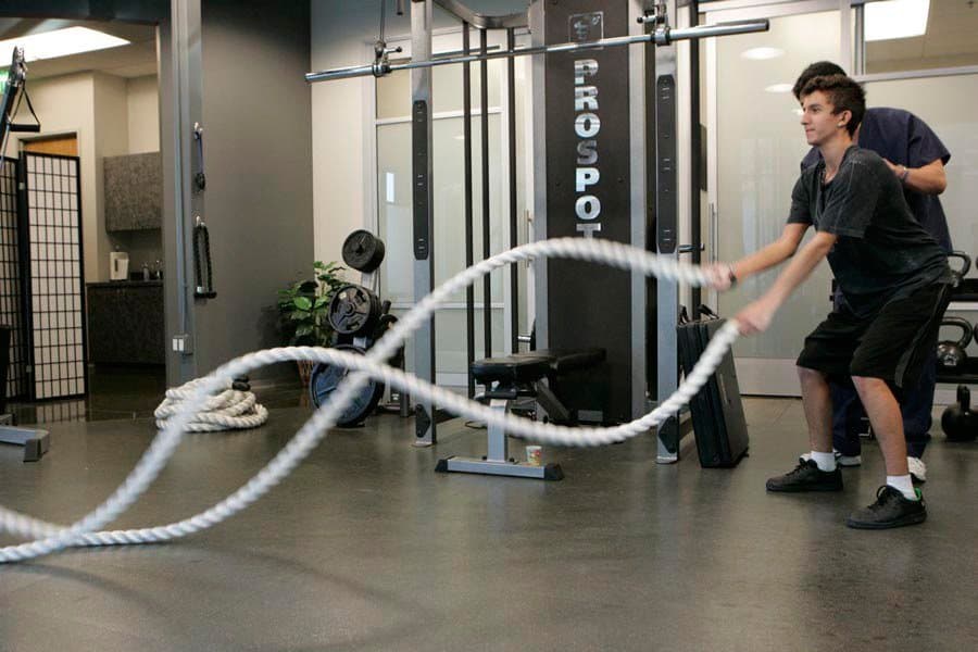 A patient making waves with heavy battling ropes on the KOH Physical Therapy Lab training floor