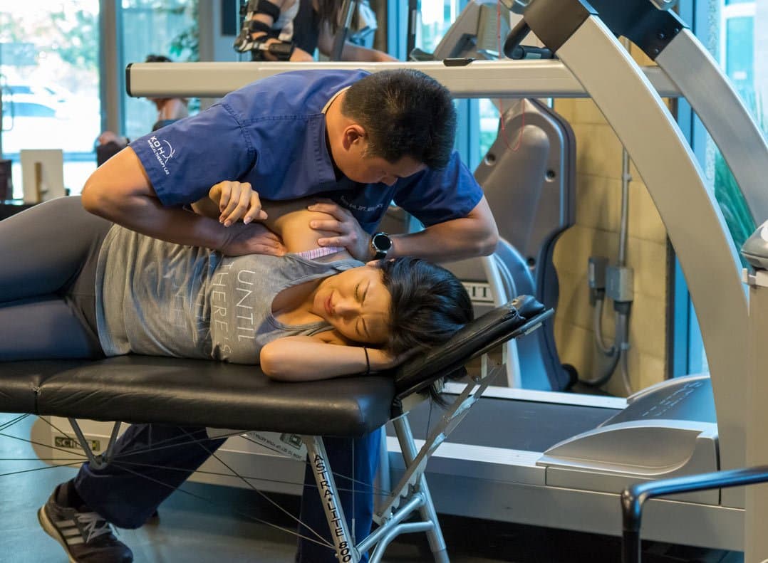Davis Koh, DPT, applying sustained hands-on pressure to the shoulder of a patient lying on her side